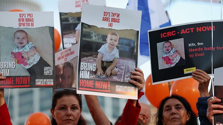 지난 28일(현지시간) 이스라엘 텔아비브에서 팔레스타인 무장 정파 하마스에 납치된 인질들의 석방을 요구하는 집회가 열린 가운데 시위대가 10개월 아기 크피르 비바스와 가족들의 사진을 들고 있다. /REUTERS=연합뉴스