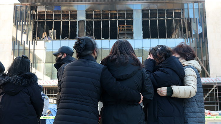  22일 오전 부산 기장군 반얀트리 리조트 화재현장에서 영정사진을 든 유가족들이 화재 현장을 보며 오열하고 있다. /연합뉴스