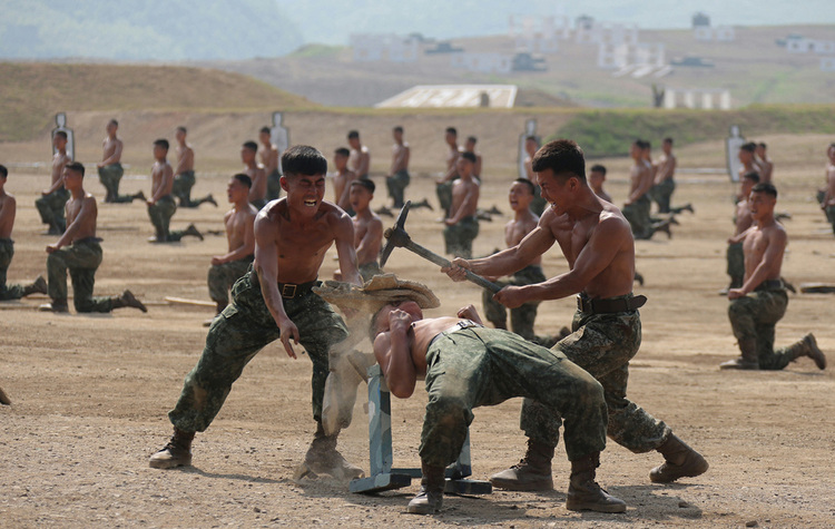 김정은이 참관한 병종별 전술종합훈련 모습. 북한군 이마 위에 올린 돌을 곡괭이로 찍어 부수는 차력쇼와 같은 훈련 모습도 포함됐다. / 조선중앙통신