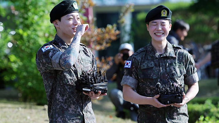 육군 병장으로 만기 전역한 BTS 지민과 정국이 11일 경기 연천군 연천공설운동장에서 열린 기념행사에서 팬들에게 인사하며 웃고 있다. /연합뉴스