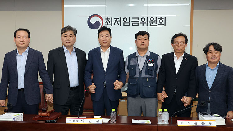 지난 10일 정부세종청사에서 열린 제12차 전원회의에서 내년 최저임금을 시간당 1만320원으로 17년만에 합의로 결정한 공익위원-사용자위원-근로자위원들이 손을 잡고 기념촬영을 하는 모습 /연합뉴스