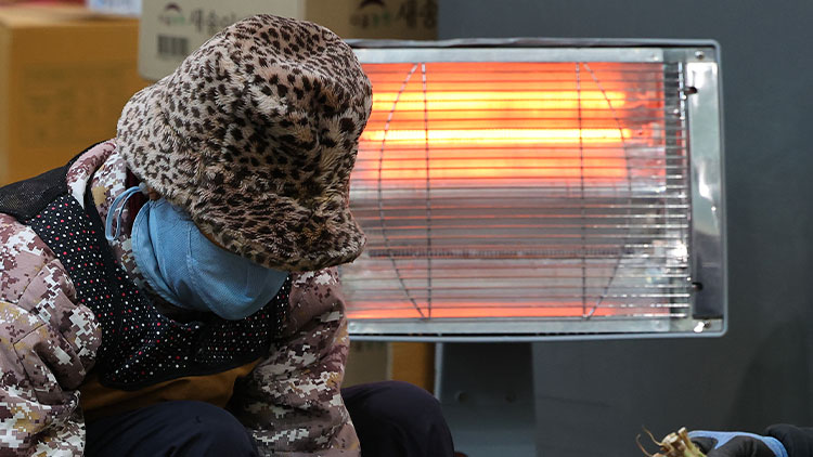 영하권의 추운 날씨를 보인 3일 오전 인천 부평구 삼산농산물도매시장에서 상인들이 전기난로에 몸을 녹이며 파를 다듬고 있다. /연합뉴스