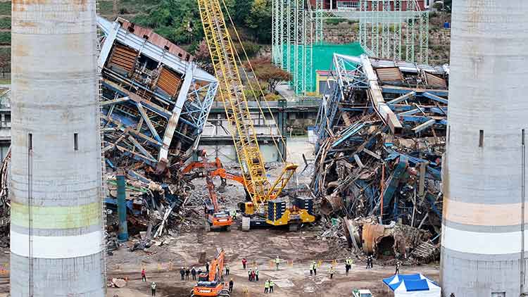 지난 12일 오후 울산화력발전소 보일러타워(5호기)에서 추가 붕괴를 막기 위해 크레인으로 상부 구조물을 고정한 뒤 중장비가 진입로를 확보하고 있다. /연합뉴스