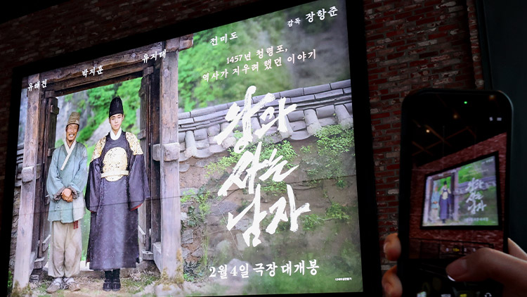 6일 서울 한 영화관에서 시민이 '왕과 사는 남자' 영화 홍보물을 촬영하고 있다. /연합뉴스