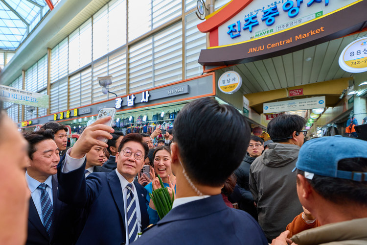 이재명 대통령이 25일 한국항공우주산업(KAI)에서 열린 KF-21 양산 1호기 출고식에 참석한 뒤 경남 진주시 진주중앙시장을 방문해 시민과 사진을 찍고 있다.  /청와대 제공 